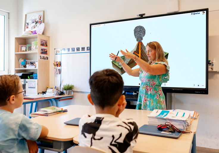 Leerkracht geeft uitleg voor de klas en een Prowise touchscreen